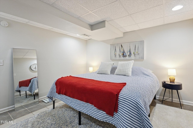 bedroom featuring a drop ceiling, visible vents, and baseboards