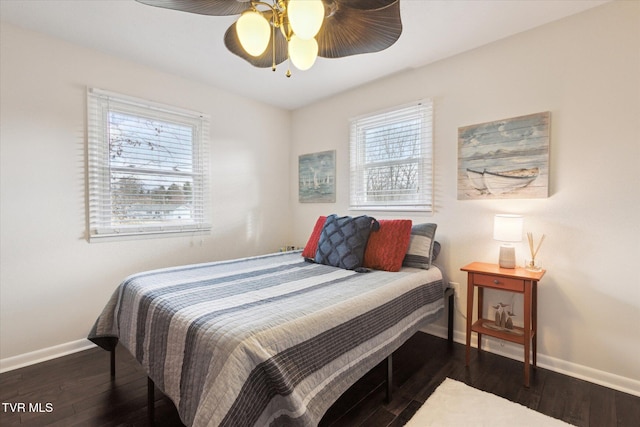 bedroom featuring baseboards, multiple windows, and wood finished floors