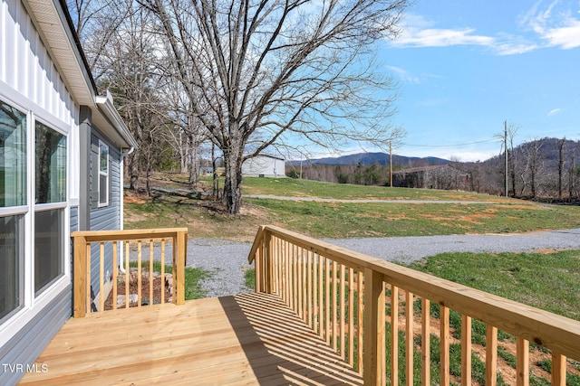 wooden deck with a mountain view and a lawn