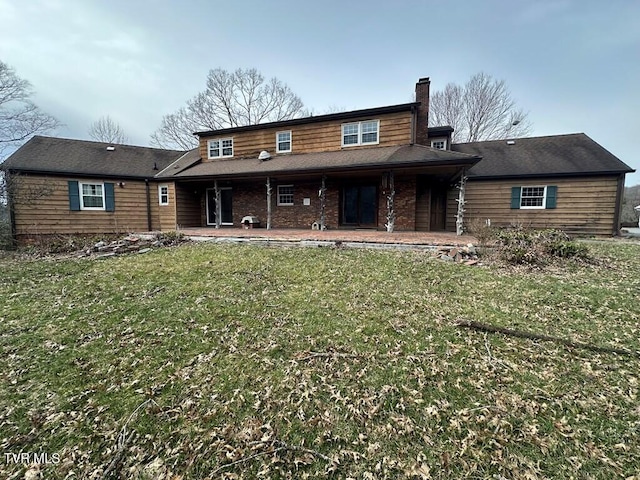 back of house featuring a patio, a lawn, and a chimney