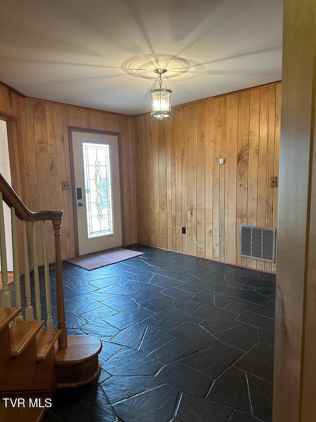 interior space with stone tile floors, visible vents, stairs, and wooden walls