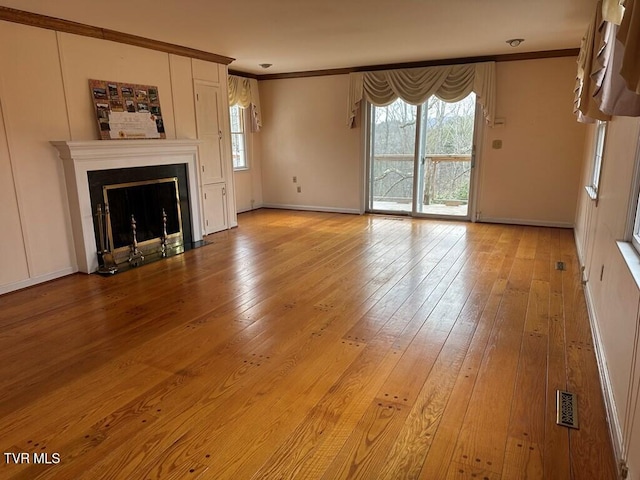 unfurnished living room with visible vents, a fireplace with flush hearth, ornamental molding, and hardwood / wood-style flooring