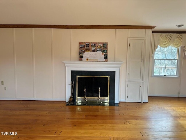 details with a decorative wall, a fireplace with flush hearth, and wood finished floors