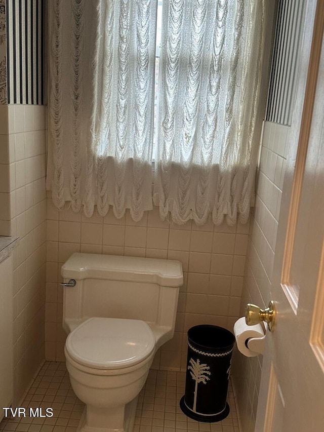 bathroom featuring tile patterned flooring, tile walls, and toilet