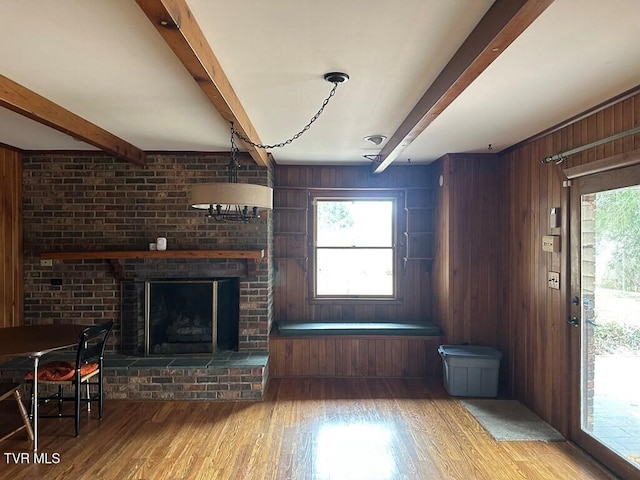 unfurnished living room featuring beam ceiling, wood finished floors, and a wealth of natural light