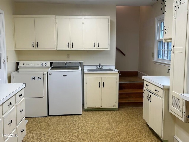 laundry room with washing machine and clothes dryer, cabinet space, light floors, and a sink