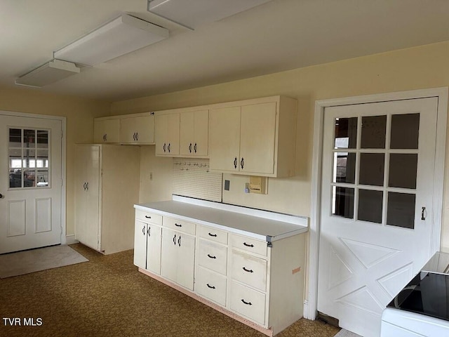 kitchen with stove, dark carpet, and light countertops