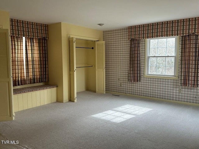 unfurnished bedroom with a closet, baseboards, carpet, and wallpapered walls