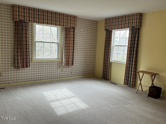 carpeted spare room with visible vents, wallpapered walls, and baseboards