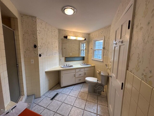 bathroom featuring wallpapered walls, a shower stall, toilet, and wainscoting