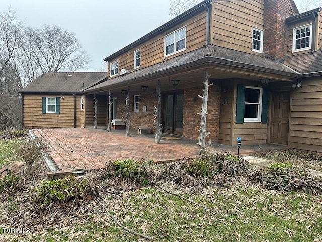rear view of property with brick siding and a patio
