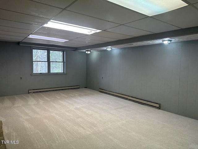 basement featuring a drop ceiling, a baseboard radiator, baseboard heating, and carpet