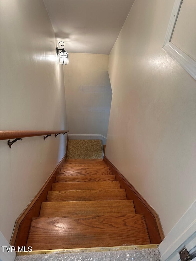 staircase featuring wood finished floors and baseboards