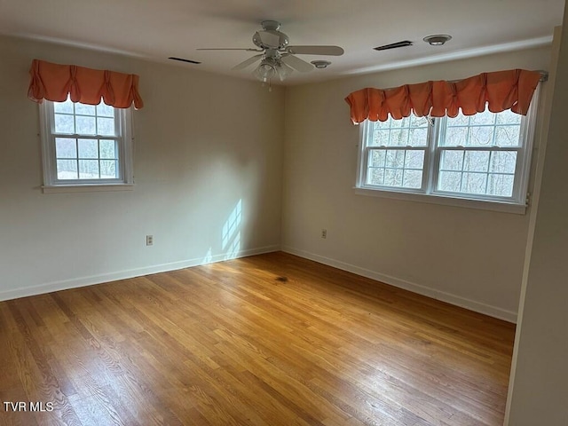 empty room with light wood finished floors, visible vents, ceiling fan, and baseboards
