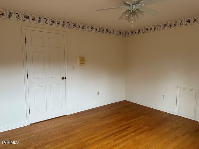 spare room with baseboards and wood finished floors