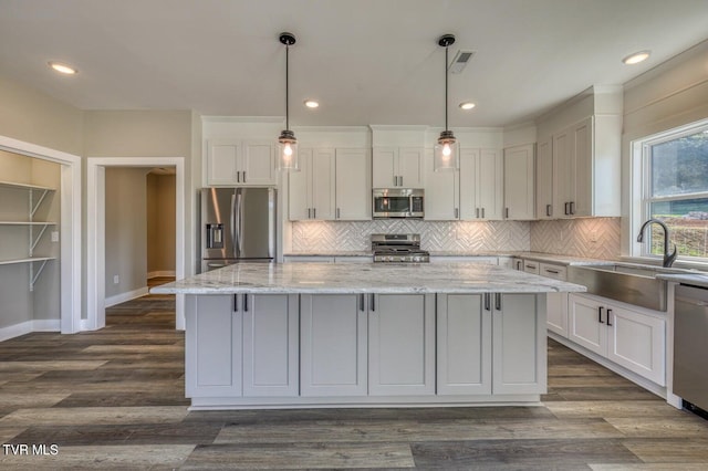 kitchen featuring a sink, dark wood-type flooring, a kitchen island, and appliances with stainless steel finishes