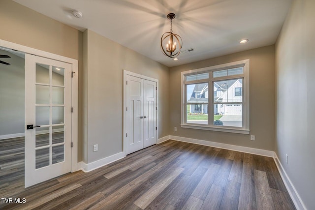 unfurnished bedroom featuring visible vents, baseboards, a notable chandelier, and dark wood-style flooring