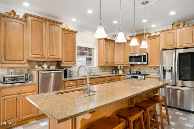 kitchen with a center island with sink, a toaster, a sink, ornamental molding, and stainless steel appliances