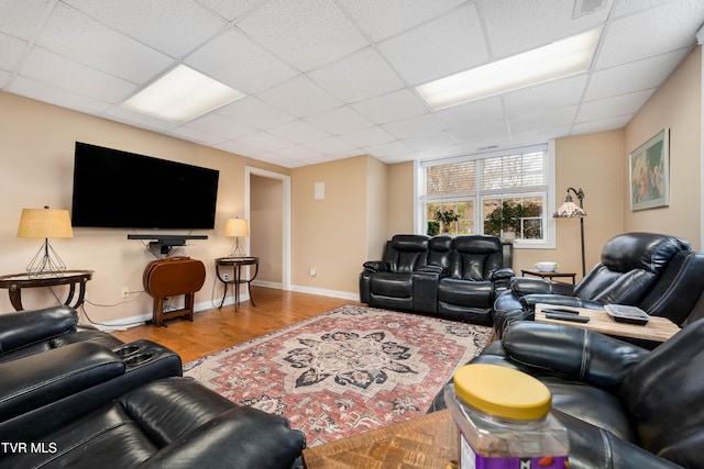 living room featuring wood finished floors, baseboards, and a drop ceiling