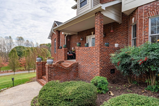 view of side of home with a porch, brick siding, and crawl space