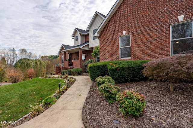 view of side of home with a yard and brick siding