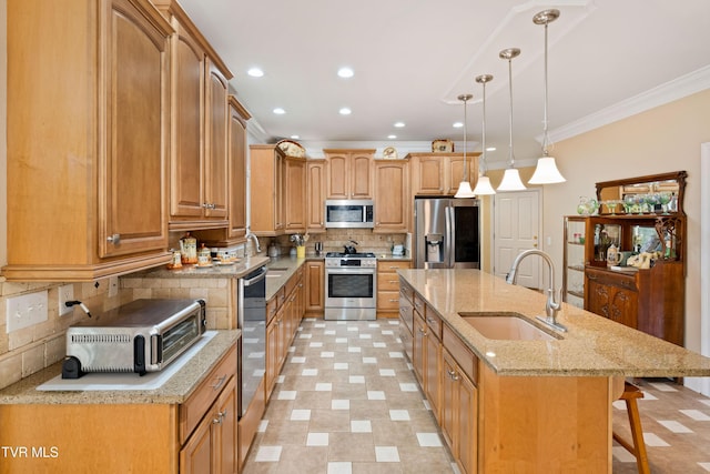 kitchen with a kitchen island with sink, a sink, stainless steel appliances, a breakfast bar area, and crown molding