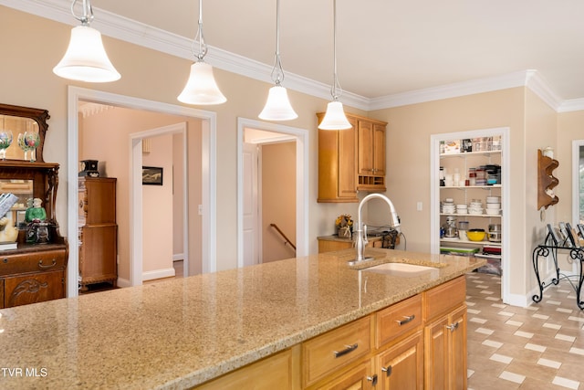 kitchen featuring a sink, light stone countertops, ornamental molding, and hanging light fixtures