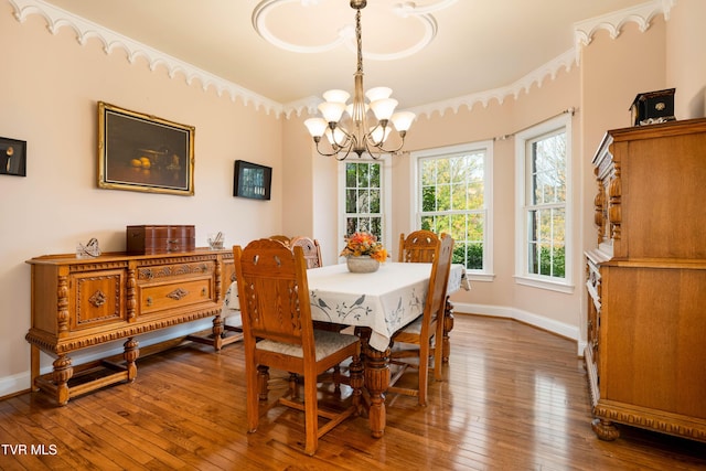 dining area featuring hardwood / wood-style flooring, a notable chandelier, baseboards, and ornamental molding