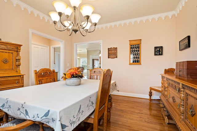 dining room with baseboards, an inviting chandelier, wood finished floors, and ornamental molding