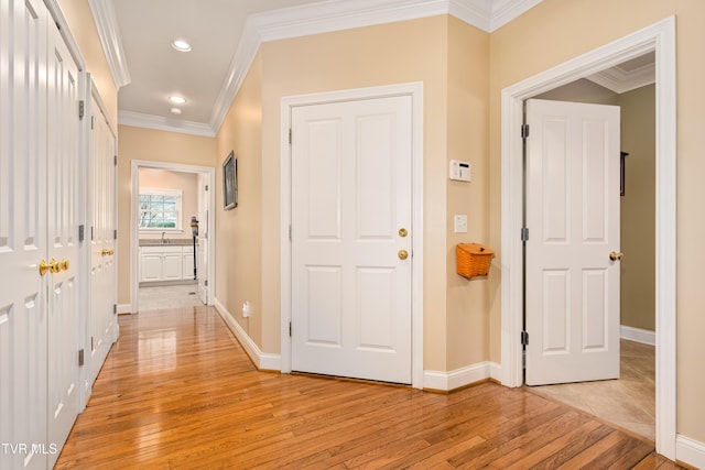 hall featuring recessed lighting, baseboards, crown molding, and light wood finished floors