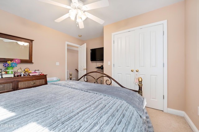 bedroom featuring a ceiling fan, baseboards, a closet, and light carpet