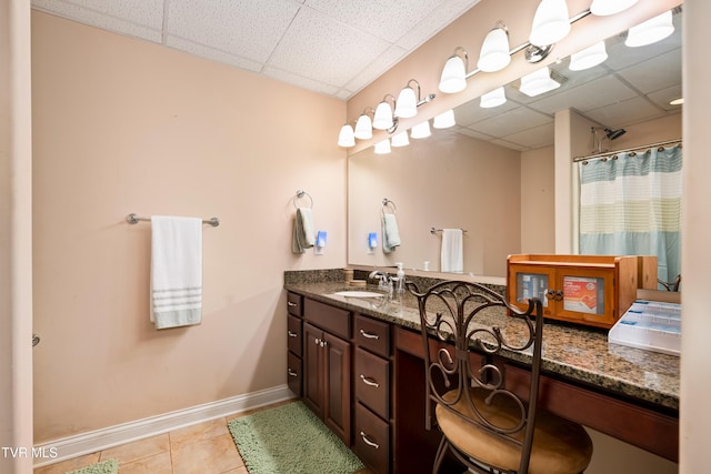 full bathroom with tile patterned flooring, double vanity, a paneled ceiling, and a sink