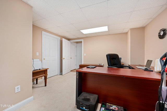 home office featuring a paneled ceiling, baseboards, and light colored carpet