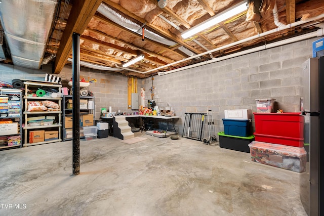 unfinished basement with electric panel and freestanding refrigerator