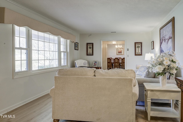 living room with baseboards, a notable chandelier, crown molding, and light wood finished floors