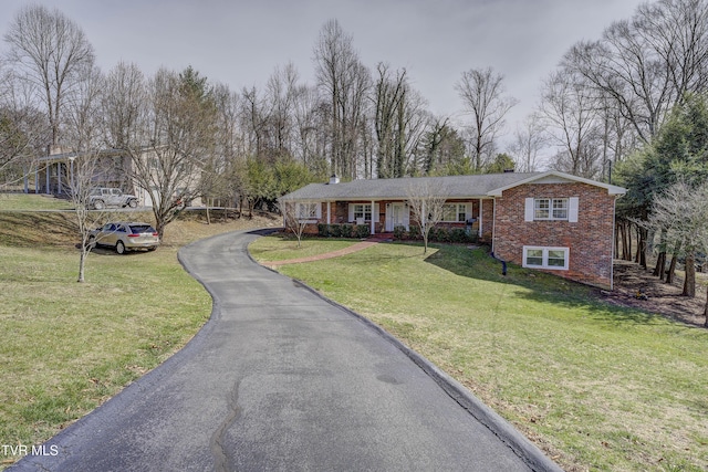 view of front of home with a front yard, brick siding, and driveway