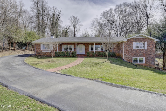 ranch-style house featuring brick siding, a porch, aphalt driveway, and a front yard