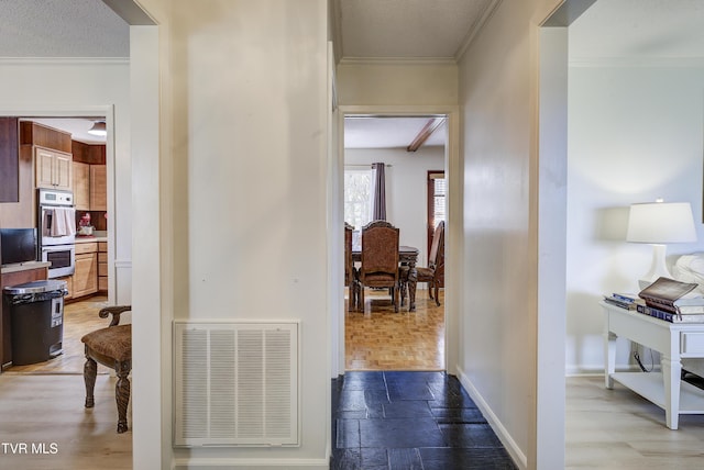 hallway featuring visible vents, baseboards, stone tile floors, and ornamental molding