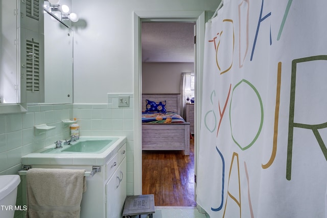 bathroom featuring toilet, tile walls, ensuite bath, and vanity