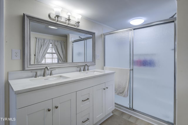 bathroom with a sink, a stall shower, double vanity, and ornamental molding