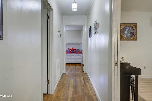 corridor featuring crown molding, wood finished floors, and baseboards