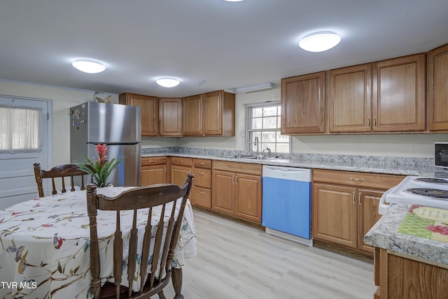 kitchen featuring dishwasher, brown cabinets, freestanding refrigerator, and a sink