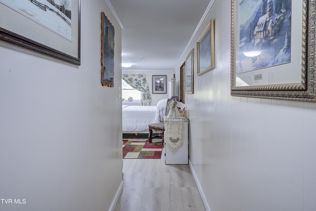 corridor with wood finished floors, baseboards, and ornamental molding