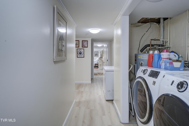 clothes washing area featuring light wood-style flooring, concrete block wall, separate washer and dryer, and baseboards