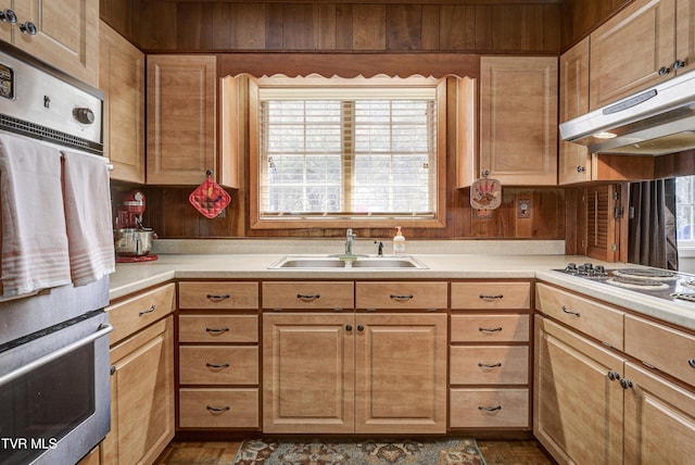 kitchen featuring stainless steel oven, light countertops, under cabinet range hood, and a sink