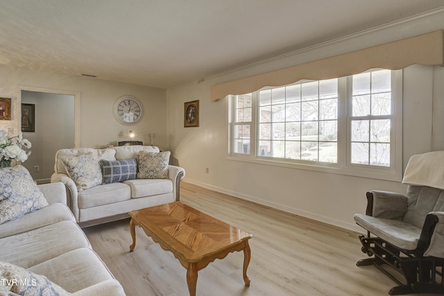 living area with light wood-type flooring, baseboards, and a healthy amount of sunlight