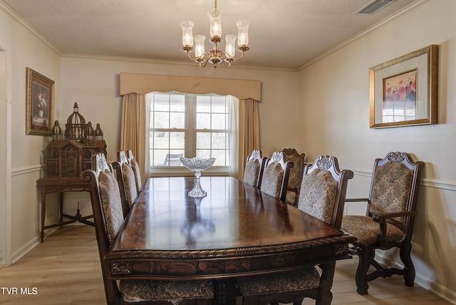 dining space with crown molding, a notable chandelier, visible vents, and light wood finished floors