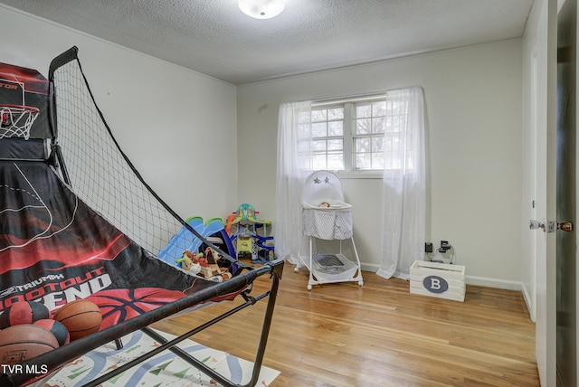 bedroom with baseboards, a textured ceiling, and wood finished floors