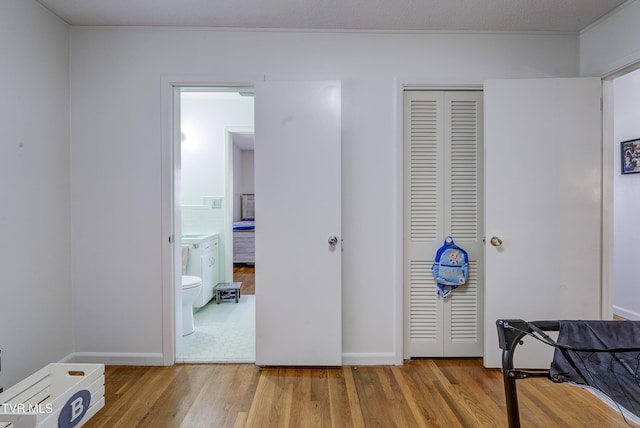 bedroom featuring ensuite bath, wood finished floors, and a closet