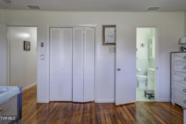 unfurnished bedroom with visible vents, a textured ceiling, a closet, and wood finished floors